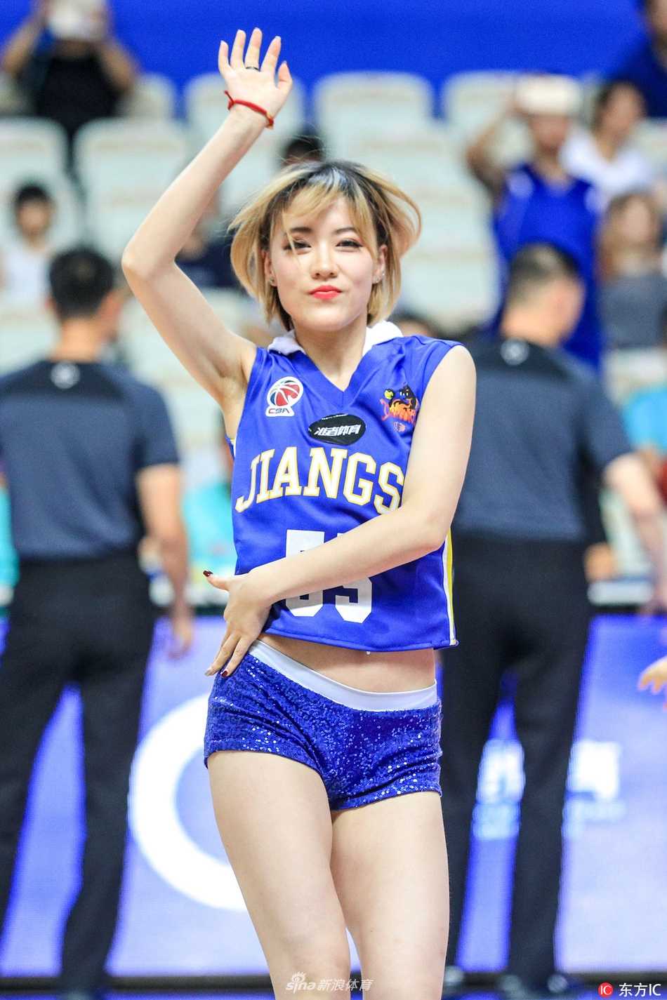 啦啦队员转身回眸，脸上洋溢着自信的笑容，手中的花球在灯光下闪耀着璀璨的光芒，青春活力感染全场。