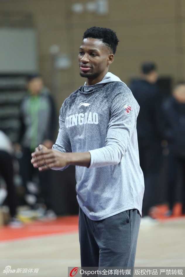 主教练手拿战术板向球员讲解防守站位，队员围成一圈认真聆听