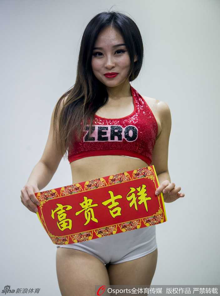 宝贝手持金色折扇，下身穿黑色短裤露出修长美腿，站在贴有‘青岛’字样的更衣室通道口，回眸一笑百媚生，职业范儿十足