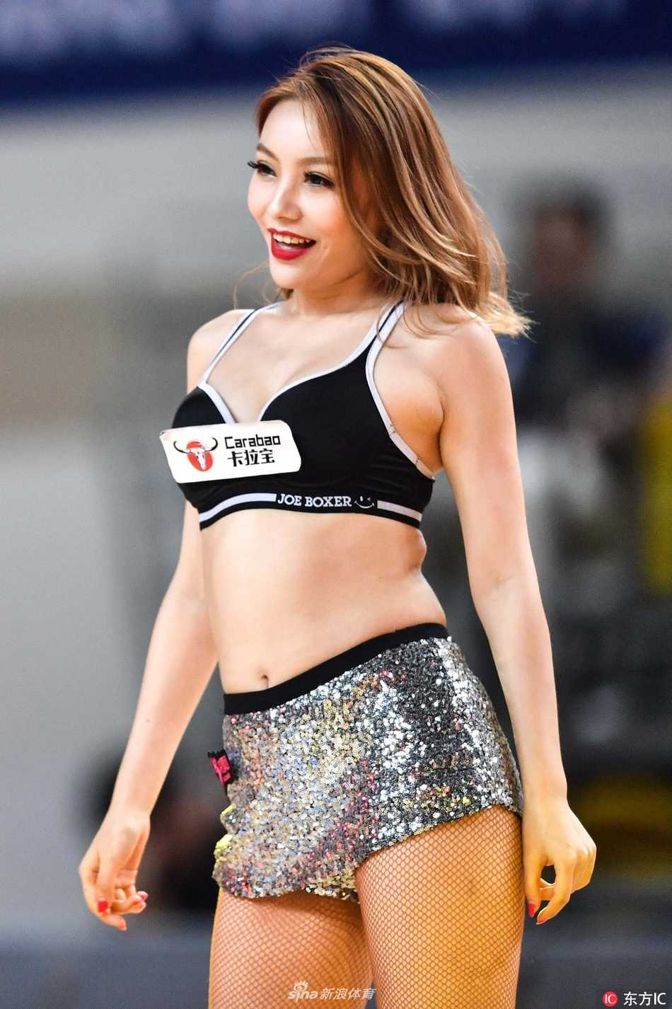 即使是静态的亮相，篮球宝贝们也姿态万千，她们单手叉腰，脸上洋溢着自信迷人的微笑，与身后巨大的赛事背景板相映成辉，定格下这美丽的瞬间。