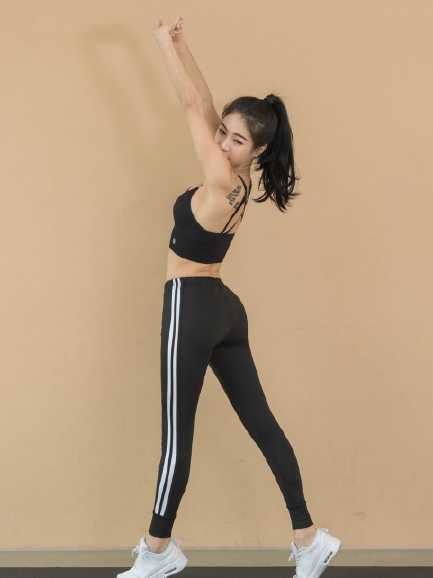 身着红色球衣的她高高跃起，在空中划过一道优美的弧线，将篮球稳稳送入篮筐。紧实的肌肉线条和修长的四肢在阳光下格外醒目，仿佛一只展翅飞翔的火烈鸟。