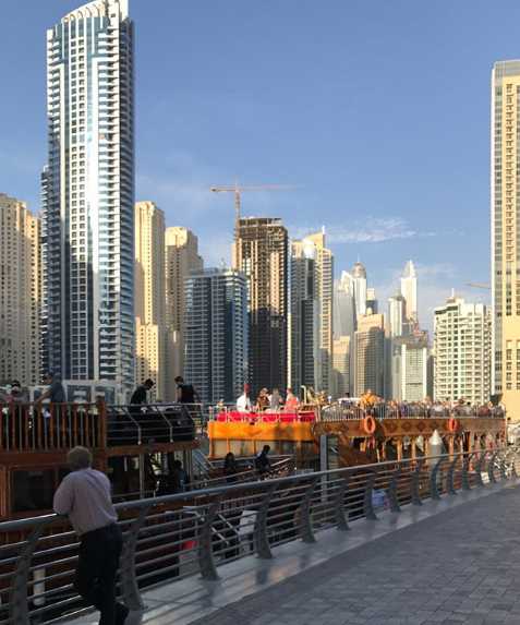 在泳池边休息的亚当斯，背景是迪拜壮观的建筑群，他正享受着温暖的日光浴，神情悠然。