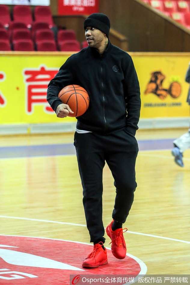 马布里单手抓球，眼神坚毅地望向篮筐，身旁的新外援正全神贯注地聆听这位CBA传奇的现场指导，空气中弥漫着专注与信任的气息。