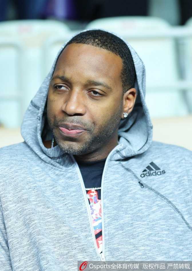 麦蒂注视着远方，嘴角带着一丝若有若无的笑意，仿佛在回忆自己当年在这片赛场上的高光时刻，眼神深邃而富有故事感。