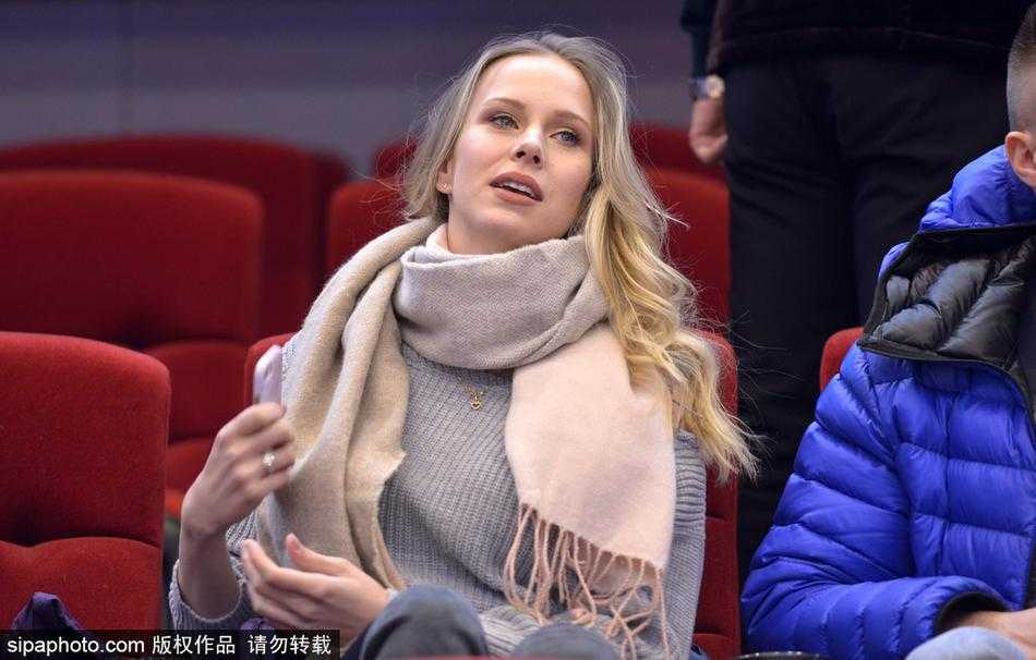 宝莲娜神情专注地盯着赛场方向，双手轻轻托腮，那份对丈夫每一次进球都充满期待的眼神，成为了冰冷看台上最温暖的守候。