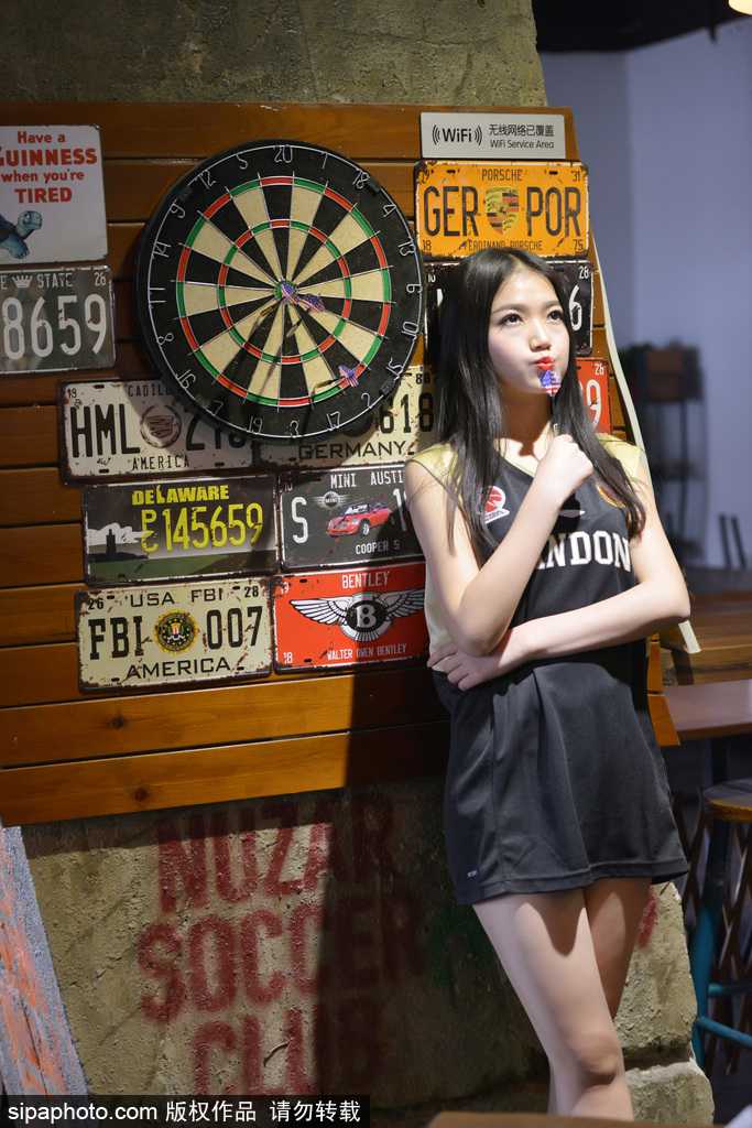 女球迷在暂停间隙低头查看手机，嘴角微微上扬，似乎是在和朋友分享此刻现场的激动心情，简约的穿搭更显其清纯本色。