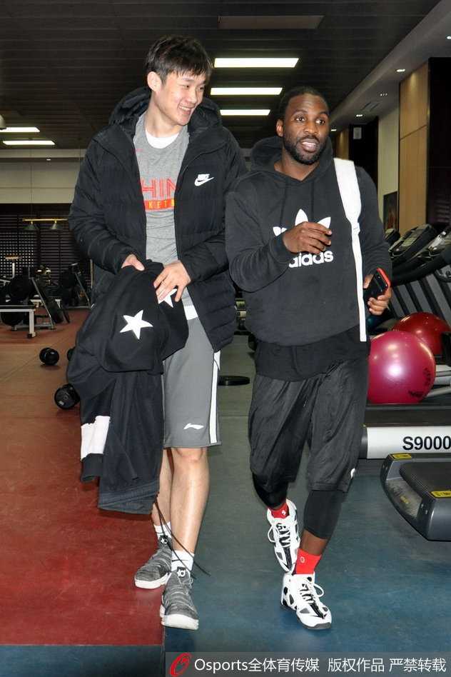 丁彦雨航在罚球线附近跳投出手，他高高跃起，滞空能力惊人。身后的训练背景虚化，更凸显了他作为球队核心的领袖气质，这一投也引来了场边队友的注视。